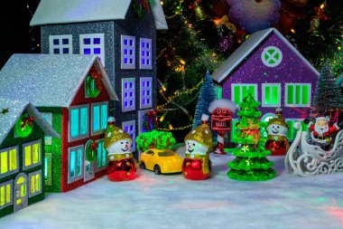 Pencerelerinde parlak ışıklar olan dört dekore edilmiş ev arasında, kardan adam şeklinde Noel süsleriyle çevrili küçük yeşil bir ağaç vardı.