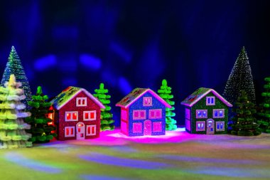 Koyu mavi bir arka planda, renkli ağaçların arasında renkli evleri olan sihirli bir kasaba.