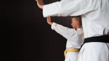 Bir antrenör ve siyah ve sarı kemerli bir atlet düz yumruklar atıyor.