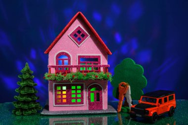 Pembe evin yanında anahtarı ve arabası olan bir Noel ağacı var.