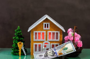 Pencerelerinde kırmızı ışıklar olan kahverengi bir ev, içinde anahtarlar, çiçekler ve yüz dolarlık banknotlar olan bir Noel ağacı ile çevrilidir.