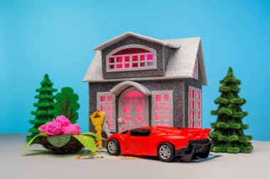 Pencereleri çiçeklerle çevrili gri bir ev ve avro banknotunun üzerinde duran kırmızı bir araba.