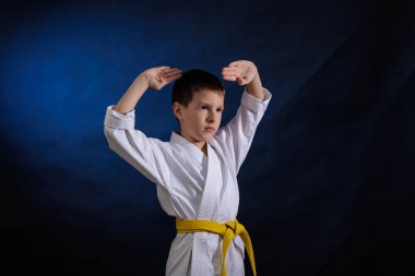 Koyu mavi arka planda, Karategi 'de küçük neşeli bir sporcu resmi egzersizler yapıyor.