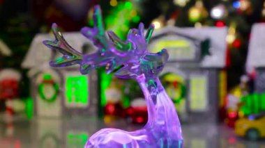 Camdan bir ren geyiği biblosu Noel kasabasının ortasında döner. Evleri ve arabaları vardır.