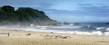 Dalgalar, Tauranga, Yeni Zelanda 'daki Deniz Geçit Töreni' nde kayalara çarpıyor.