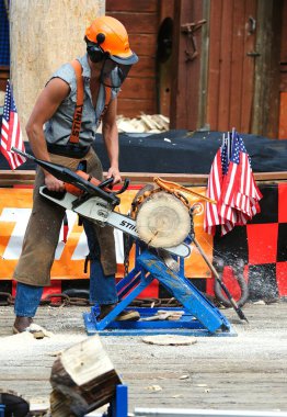 Ketchikan, Alaska, USA - 1st July 2023:Lumberjack using a powerful chainsaw to to cut a log clipart