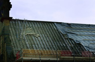 An old large roof under repair, showing ladders and battens clipart