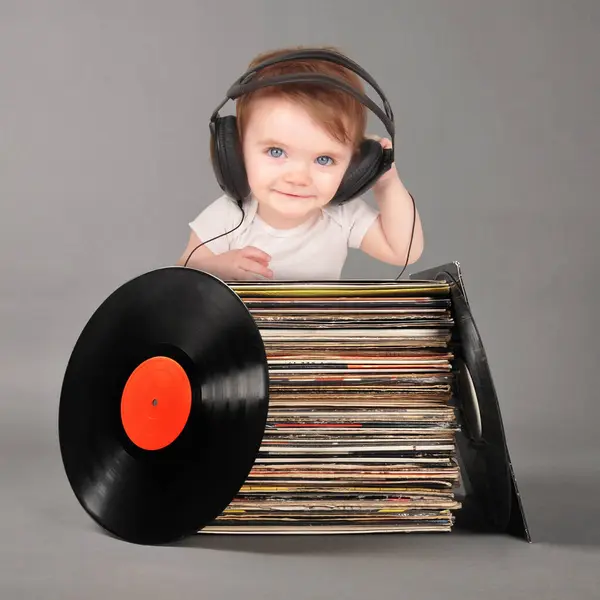 Şirin bir bebek eski retro plakların yanında oturmuş bir çocuk gelişimi ya da şarkı seçimi mesajı için kulaklıkla müzik dinliyor..