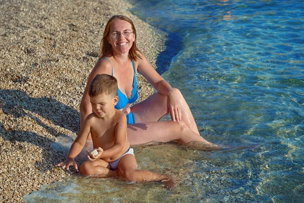 克罗地亚波雷奇度假胜地 快乐的母亲和小儿子坐在海滩上 — 图库照片