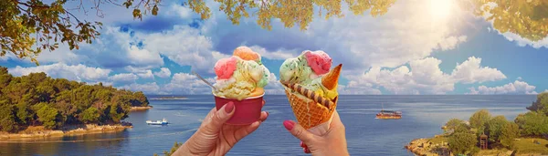 Wonderful romantic summer afternoon landscape panorama of a couple with beautiful bright sweet ice cream of different flavors in the hands and sea on background. Green lagoon sea bay in Porec, Croatia - Istria, Europe .Traveling concept background