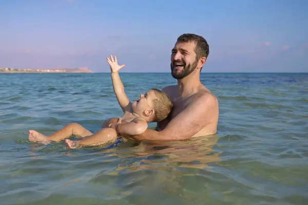 快乐的父亲和儿子在海滩上玩水 暑假快乐的生活方式童年的概念 图库图片