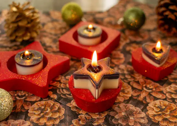 Star tea light holder with burning tea light in red with glitter dust. The candles are two-tone with glitter.