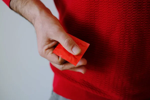 Man Hand Holding Condom Red Sweater Valentines Day Holiday — Φωτογραφία Αρχείου