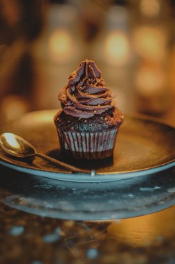 Chocolate cupcake with cacao cream on coffee shop marble counter. Blur background