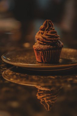 Chocolate cupcake with cacao cream on coffee shop marble counter. Blur background