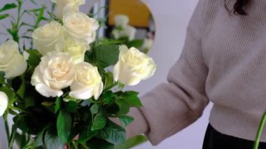 Professional woman florist preparing a bouquet of white roses for sale or delivery. High quality 4k footage close up hands