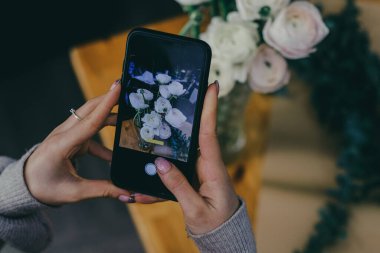 Çiçekçi sosyal medya içeriği cep telefonunu kapatıp Ranunculus buketinin fotoğraflarını çekiyor. Yüksek kalite fotoğraf