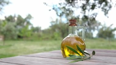 Zeytin bahçesindeki ahşap bir masada bir şişe ekstra saf zeytinyağı. Arnavutluk