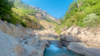 Muhteşem kanyon Shkallet e Tujanit ve onun Tiran, Arnavutluk 'taki kayalık yamaçlar arasındaki akıntıları. Kadın turist güneşlenmeyi seviyor.