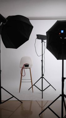 Fotoğraf stüdyosunda profesyonel ışıklandırma ekipmanlarıyla çevrili boş tabure.. 