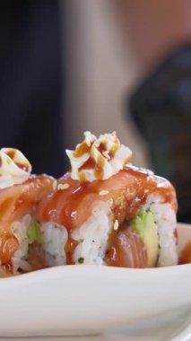 Şef suşi yapıyor, üzerine susam tohumu serpiştiriyor. Taze suşi. Japon suşi rulo makro yakın görünüm, bulanık arkaplan 