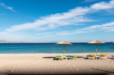 Kumlu sahilde şemsiyesi ve sandalyesi olan güzel bir sahil.
