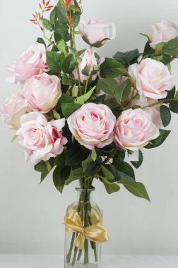 Beyaz arka planda vazoda pembe güller.