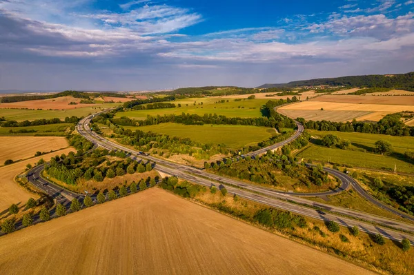 Aerial bird view of typical Ardennes green field meadows and hill landscape also showing highway and buildings in te far background of this german environment. Germany.