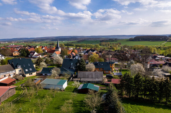 Village surrounded by beautiful hilly green landscape at a colorful sunrise, aerial footage. Germany.