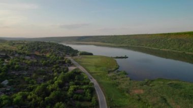 İnsansız hava aracının Dniester nehrinin kıyısında beyaz bir kilisesi olan bir peri masalı köyünün üzerinden uçuşu. Moldova Cumhuriyeti.