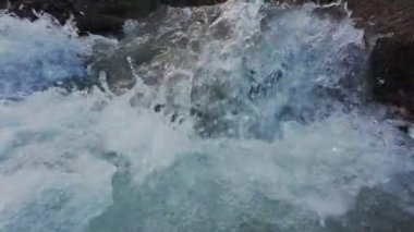 Canlı ve su sıçratan küçük bir dağ deresi gibi. Taze kaynak suyu yosunlu ve karla kaplı kayaların arasından geçiyor. Yavaş çekim.
