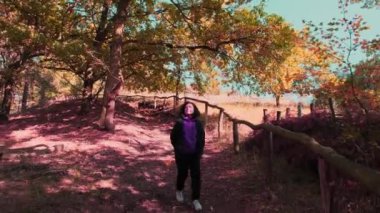 Rear view of a woman travels through an autumn forest