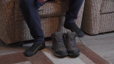 Person laces up hiking winter boots indoors. Close up of man put on trackers, and preparing himself
