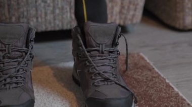 Person laces up hiking winter boots indoors. Close up of man put on trackers, and preparing himself