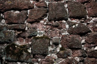 Kaba bir dokusu olan taştan yapılmış bir duvar. Duvar kahverengi ve beyaz.