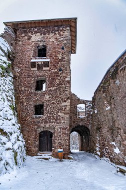 Karla kaplı çatısı ve çan kulesi olan bir kale. Kale karlı bir manzarayla çevrilidir. Hohnstein Kalesi 'nin yıkıntısı, Harz dağları, Almanya.