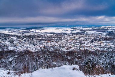 Uzakta bir kasabası olan karlı bir manzara. Gökyüzü bulutlu ve kar zemini kaplıyor. Almanya.
