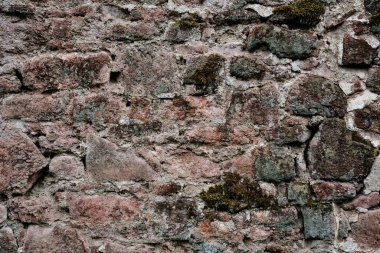 Kaba bir dokusu olan taştan yapılmış bir duvar. Duvar kahverengi ve beyaz.