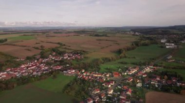Sonbaharda Almanya 'da küçük bir köyün üzerinde hava manzarası. Tarlalar sarı ve yeşildir ve güneş batıyor ve uzun gölgeler görebilirsiniz.