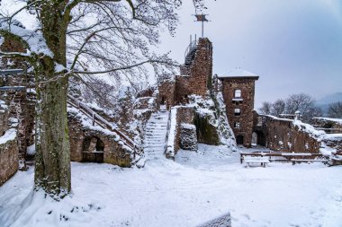 Karla kaplı çatısı ve çan kulesi olan bir kale. Kale karlı bir manzarayla çevrilidir. Hohnstein Kalesi 'nin yıkıntısı, Harz dağları, Almanya.