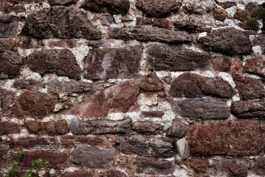 Kaba bir dokusu olan taştan yapılmış bir duvar. Duvar kahverengi ve beyaz.