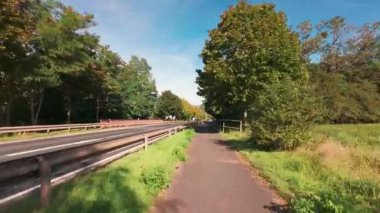 Sonbaharda kırsal bir kasaba yolunda araba sürmek. FPV yol boyunca gidiyor. Sokakta araba kullanan ilk kişi. Almanya.