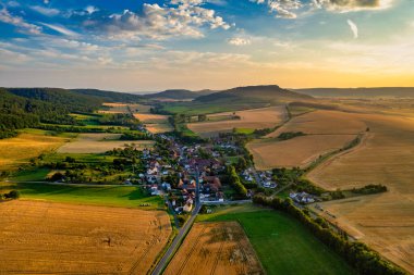 Büyüleyici Alman köyü, gür bir vadi boyunca yayılıyor, canlı çatıları ile mavi gökyüzünün altında, tüylü bulutlarla süslenmiş manzarayı noktalıyor. Doğa her yönde gelişir. Almanya.