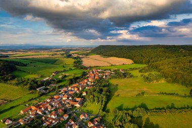 Büyüleyici Alman köyü, gür bir vadi boyunca yayılıyor, canlı çatıları ile mavi gökyüzünün altında, tüylü bulutlarla süslenmiş manzarayı noktalıyor. Doğa her yönde gelişir. Almanya.