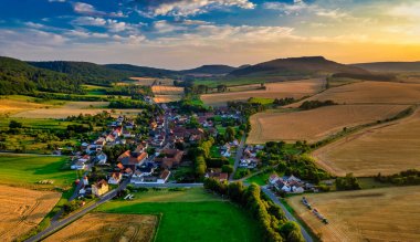 Büyüleyici Alman köyü, gür bir vadi boyunca yayılıyor, canlı çatıları ile mavi gökyüzünün altında, tüylü bulutlarla süslenmiş manzarayı noktalıyor. Doğa her yönde gelişir. Almanya.