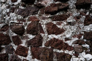 Kaba bir dokusu olan taştan yapılmış bir duvar. Duvar kahverengi ve beyaz.