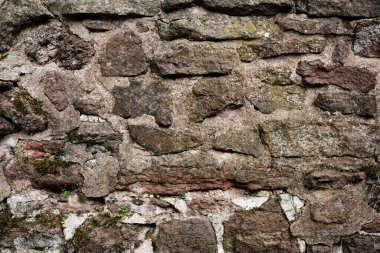 Kaba bir dokusu olan taştan yapılmış bir duvar. Duvar kahverengi ve beyaz.