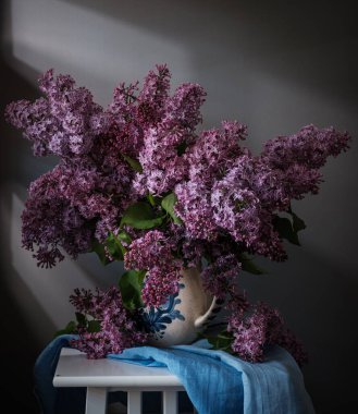 Güzel leylak çiçekleri zarif bir sepetin içinde sergilenir, sakinlik ve güzellik hissi uyandırır.