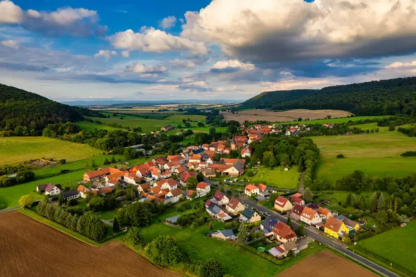 Büyüleyici Alman köyü, gür bir vadi boyunca yayılıyor, canlı çatıları ile mavi gökyüzünün altında, tüylü bulutlarla süslenmiş manzarayı noktalıyor. Doğa her yönde gelişir. Almanya.