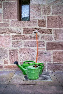 Taş bir duvarın karşısında duran plastik bahçe fıskiyeleri. Bir ülke konsepti.